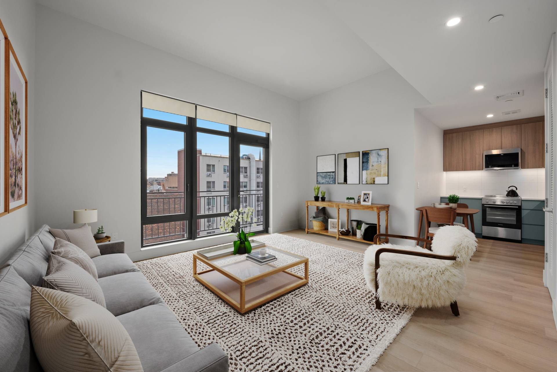 Modern, bright Living Room with light wood floors, light walls, couch, seating and tables, and opens up toe modern kitchen