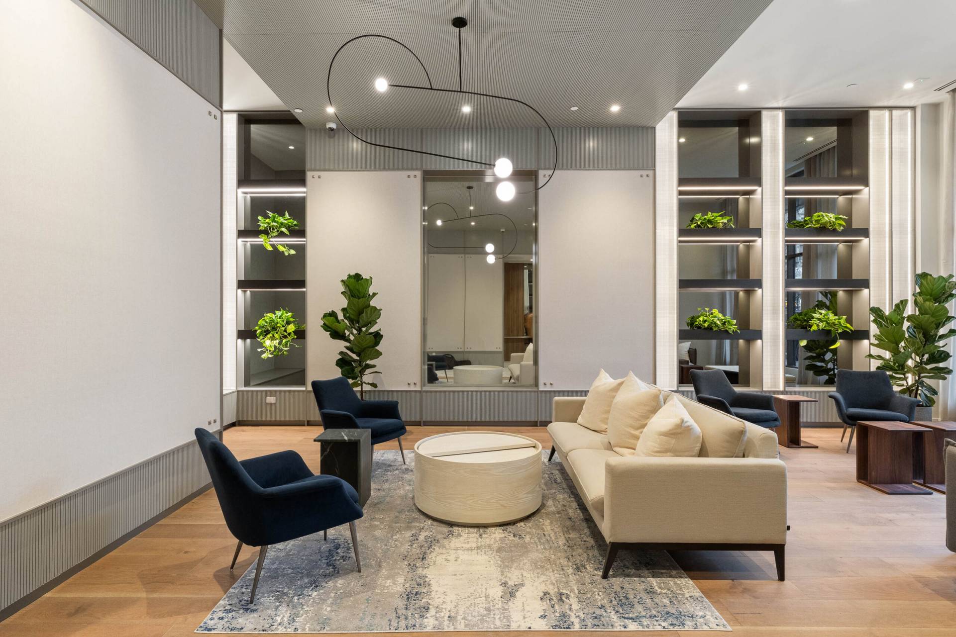 Modern lobby with contemporary couch and chairs, wood flooring, built in shelfs with plants